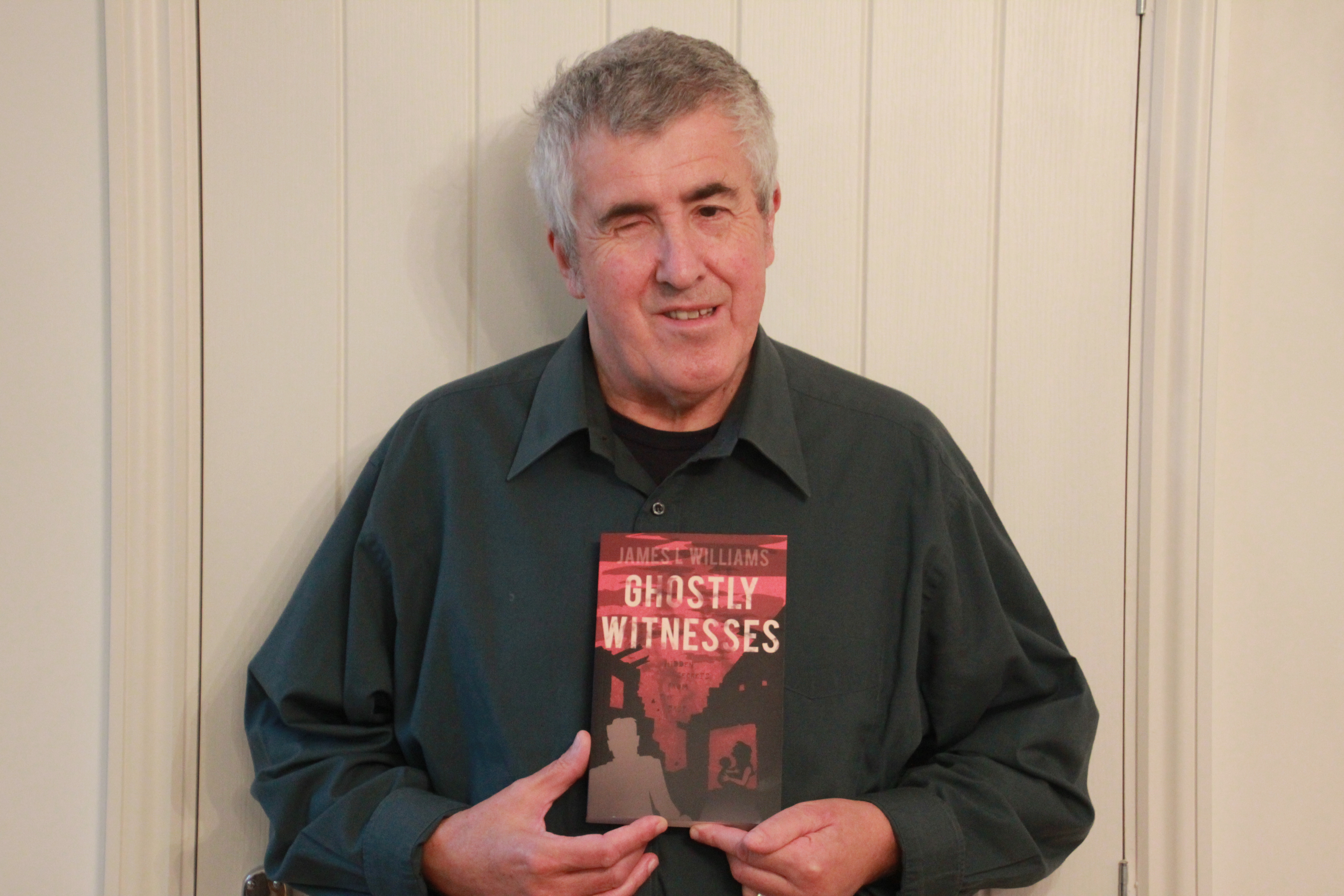 A picture of James Williams holding a copy of Ghostly Witnesses.